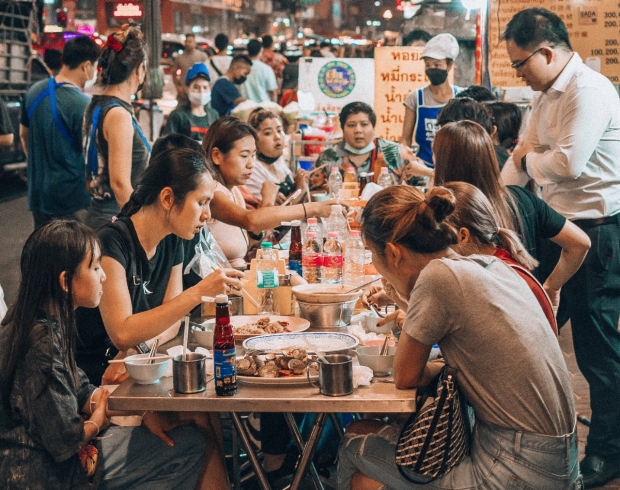 a group of people sitting at a table in the middle of a street from Unsplash.com